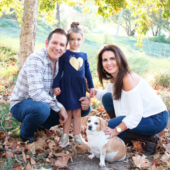 The Llopis Family posing for a photo with their dog.